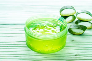 a jar with bright green gel and aloe cut leaves