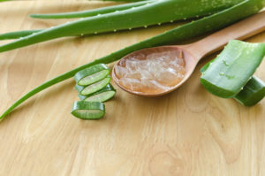 Aloe vera leaves and translucent gel on a wooden spoon