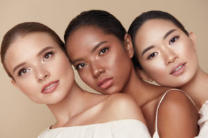 three women leaning on each other, caucasian, black and asia